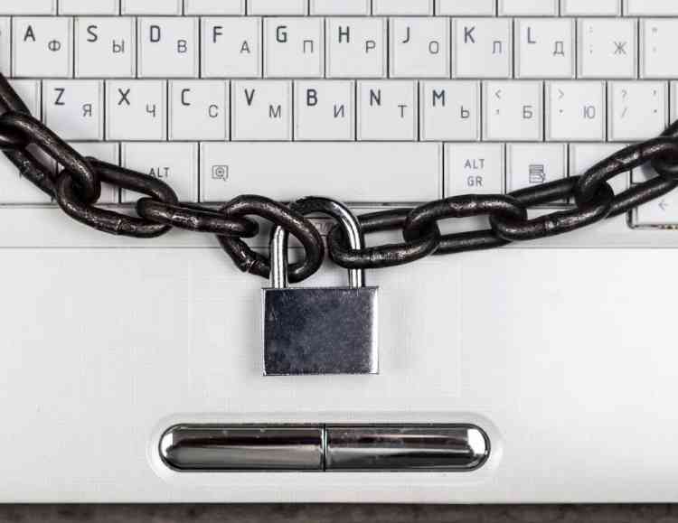 a computer locked witha chain and key lock representing cybersecurity