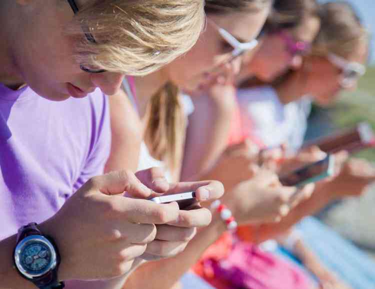 group of teenagers using phones to send messages